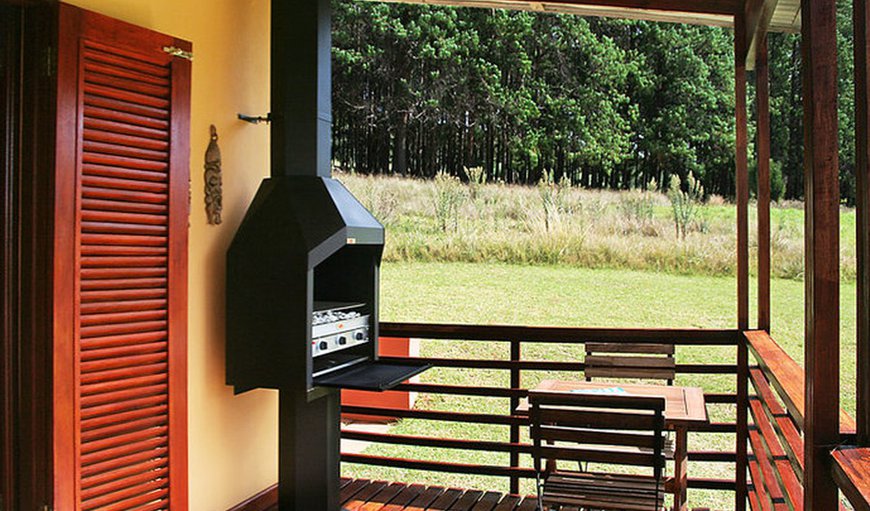 Wooden shutters open up onto a patio with braai facilities and an outdoor dining table.